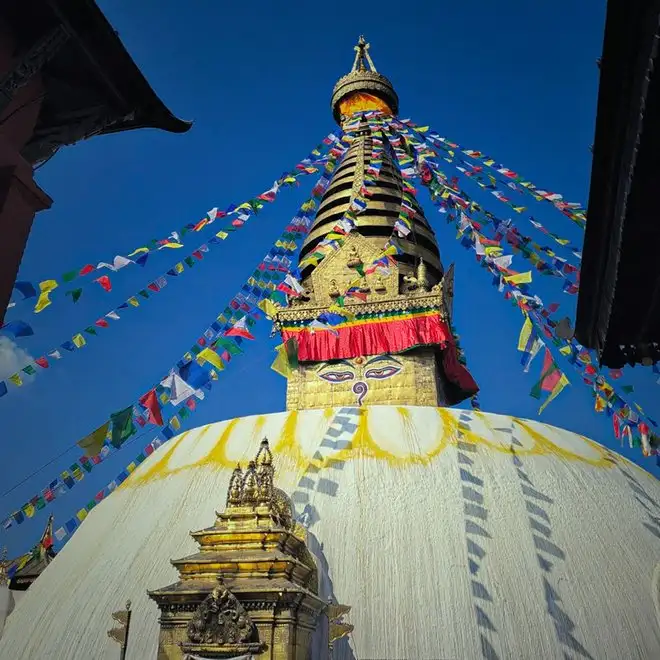 A stupa strung with prayer flags under a blue sky